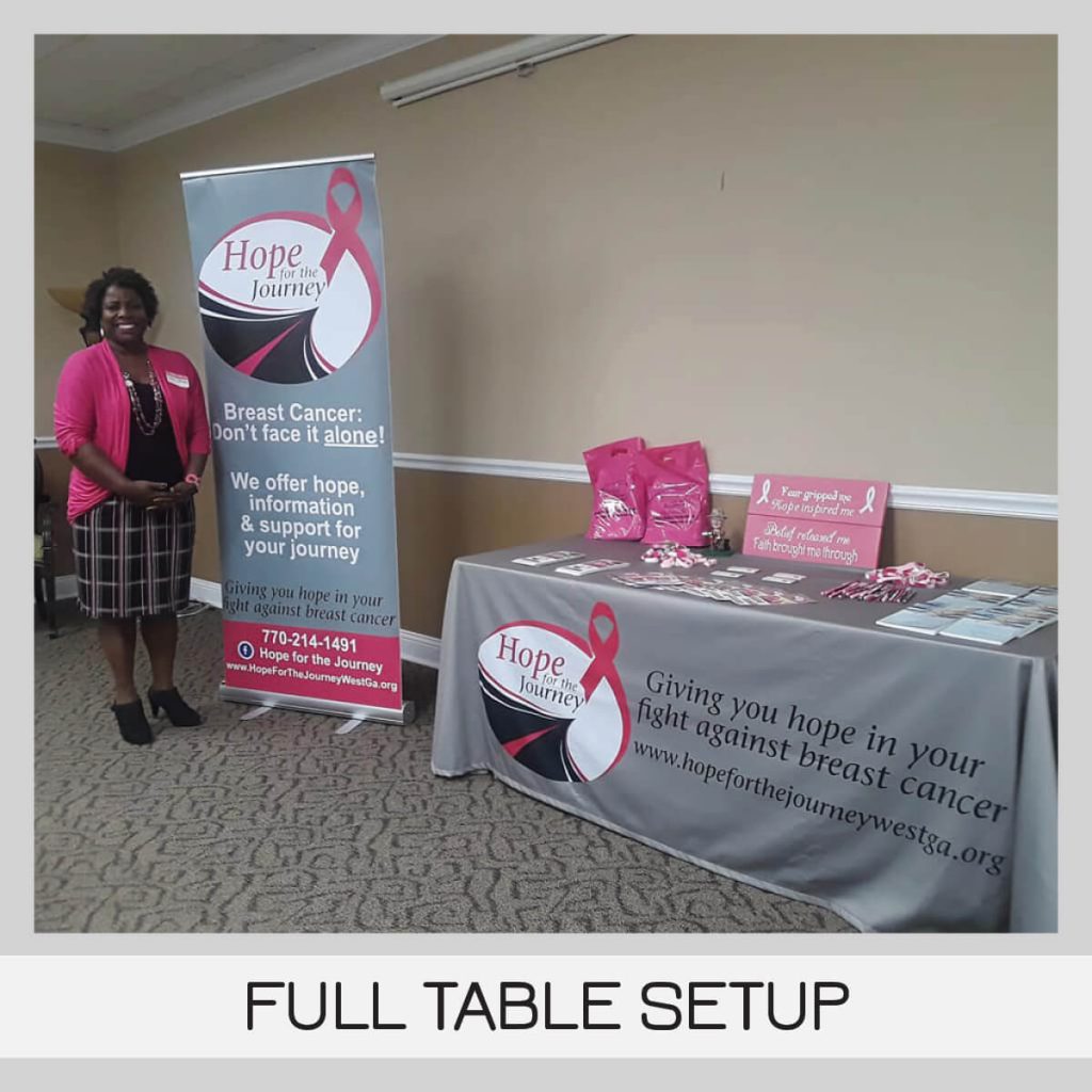 Large free-standing banner next to 8 foot table covered by tablecloth and large branded business banner, handouts and other event materials for Hope for the Journey