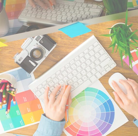 Picture of person sitting at desk with multiple color wheels and color palettes strewn around the desk